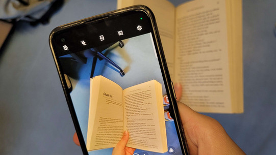 Dekoratives Foto von einem Handy, das ein Foto von einem Buch macht